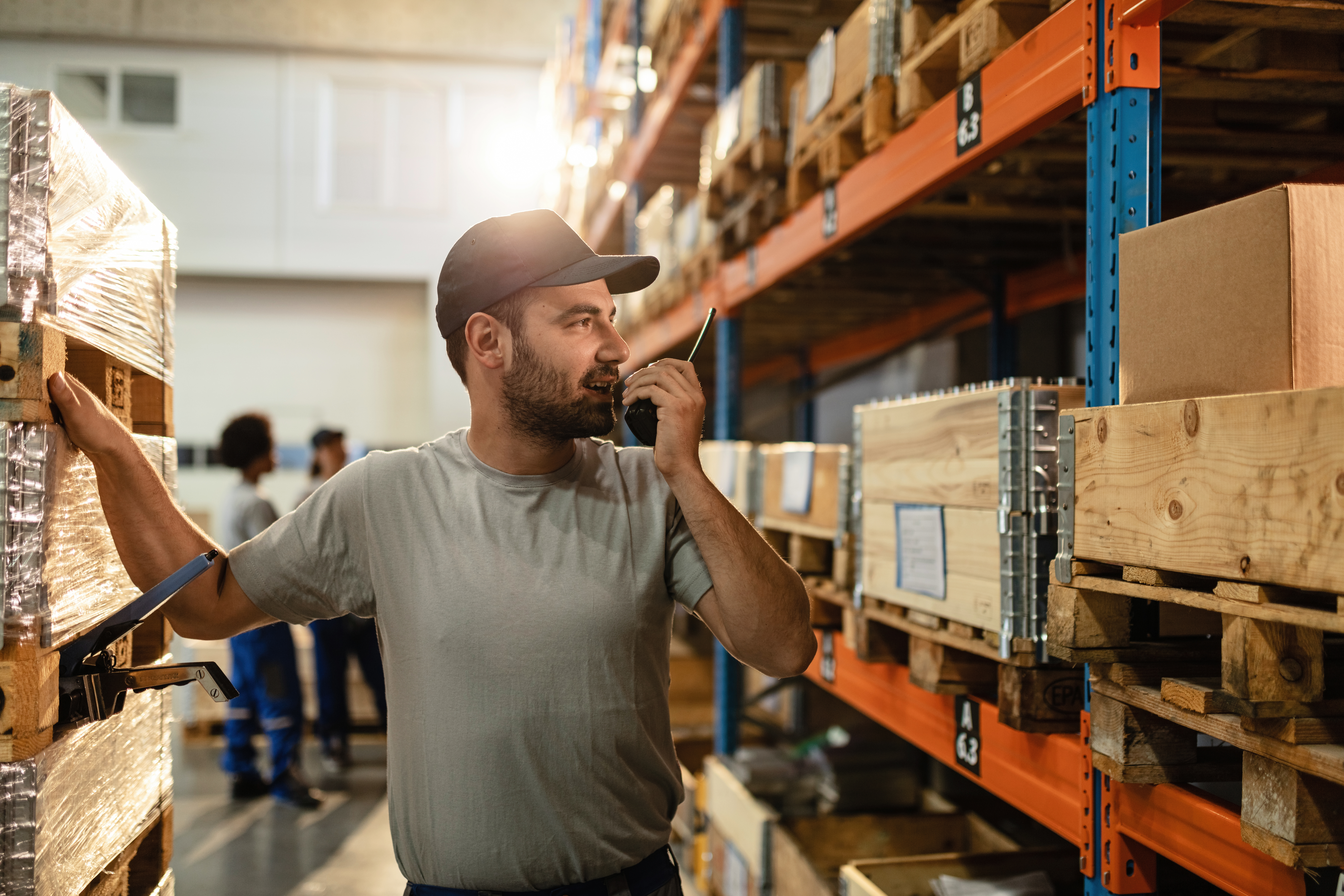 Young worker using walkie-talkie while working in a warehouse.